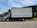 A 2016 Isuzu NRR box truck with a white cargo box and a black chassis parked on a street