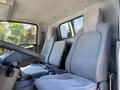 Interior of a 2016 Isuzu NPR-HD featuring two gray fabric seats with armrests and a steering wheel visible in the foreground