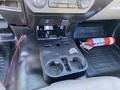 The interior console of a 2018 Ford F-150 featuring cup holders a storage compartment and a fire extinguisher placed on the floor
