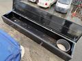 A large, black toolbox with an open lid, revealing an empty interior and a small bucket of sand placed inside.