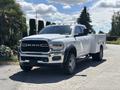 A 2021 RAM 5500 pickup truck in white with chrome accents and a utility bed parked on a roadway