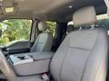 Interior of a 2017 Ford F-550 with two front seats and a center console showing fabric upholstery and a storage compartment