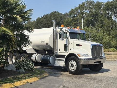 A white 2008 Peterbilt 340 truck with a silver tanker body and orange warning lights parked on a concrete surface