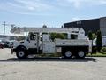 A white 2006 International 7500 utility truck with a mounted aerial lift and equipment compartments on the sides
