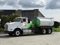 A white 1996 Kenworth T800 truck with a green and silver tank trailer parked on a concrete surface