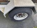 Close-up of the tire on a 2014 Express 8 Foot Trailer showing the wheel rim and tread with some rust on the bolts