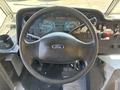 Steering wheel of a 2012 Ford Econoline with the Ford logo visible in the center dashboard displays various gauges and controls
