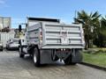 A 2011 International WorkStar dump truck with a silver body and black wheels is parked in a lot featuring a covered bed and several rear lights
