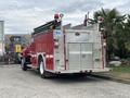 A red 2002 GMC C7500 fire truck with a silver metallic rear compartment and various hoses mounted on top