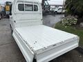 A 2010 Suzuki Carry with an open flatbed in the foreground showcasing its white cargo area
