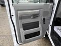 Interior door panel of a 2022 Ford Econoline featuring a gray design with a handle and storage compartments