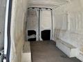 The interior of a 2019 Mercedes-Benz Sprinter van showing insulated walls and two benches along the sides with a white finish and bare floor