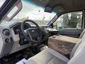 Interior of a 2008 Ford F-450 featuring a black steering wheel with controls a beige seat and a wooden box in the passenger area