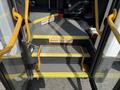 A set of metal steps with yellow safety edges leading into a vehicle with a "Watch Your Step" sign on the steps