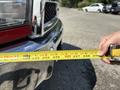 A red 2013 RAM 2500 truck with chrome accents is being measured with a yellow tape measure held in a person's hand
