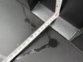 A measuring tape laid out on a dark surface with water droplets nearby