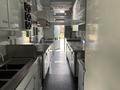 Interior of a 2020 Freightliner MT45 food truck featuring stainless steel countertops and appliances with an open layout and workstations on both sides
