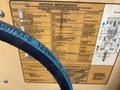 A close-up of a black hydraulic hose marked with specifications and a maintenance chart for a 2012 John Deere 310SJ