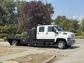 A white 2005 GMC C7500 Topkick truck with a flatbed and an enclosed compartment on the side parked on a street
