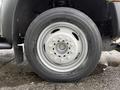 Close-up of a silver wheel and tire of a 2013 Ford F-450 SD showing multiple lug nuts and a black tire tread pattern