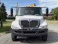 A 2011 International 4300 truck facing forward with a white cab and chrome grille featuring horizontal bars and amber lights on top