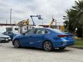A blue 2021 Kia Forte parked with a sleek design and sporty wheels visible from the rear angle
