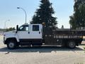 A 2005 GMC C7500 Topkick truck in white with a flatbed and black toolboxes on the side