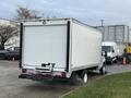 A white 2022 Ford E-450 box truck parked with its rear doors closed and visible exhaust mist coming from underneath the vehicle