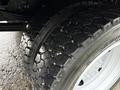 Close-up of a tire from a 2015 Hino 195 showing deep tread patterns and a shiny rim