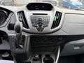 Dashboard of a 2017 Ford Transit displaying controls for audio and climate settings with gear shift and cup holders visible