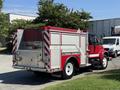 A red and white 1991 International 4600 fire truck with reflective stripes and a silver storage compartment on the rear