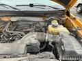 Close-up of the engine compartment of a 2014 Ford F-150 showing various engine components and a coolant reservoir