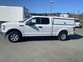 A white 2017 Ford F-150 pickup truck with a matching canopy on the bed and alloy wheels