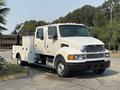 A white 2006 Sterling Acterra truck with a flatbed and utility features, featuring dual front seats, visible headlights, and orange clearance lights on the roof
