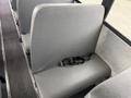 A row of gray bus seats with a black seatbelt on one of the seats inside a vehicle