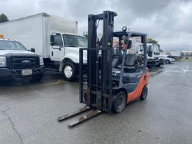 A 2011 Toyota 028FG15 forklift with a black frame and orange accents is positioned prominently in the foreground with its forks lowered