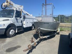 A 2010 aluminum 16 foot boat with a flat bow and a rear cabin structure on a trailer ready for transport
