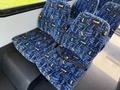 A row of blue patterned fabric seats with seatbelts inside a vehicle