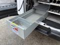 A large metal drawer pulled out from the interior of a 2016 GMC Savana van showing a smooth grey interior and a metal divider