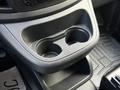 A close-up view of the center console in a 2020 Mercedes-Benz Metris featuring two cup holders and a lower storage compartment