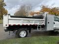 A silver 2012 Ford F-550 dump truck with a black tarp over the bed and a side compartment for tools and equipment