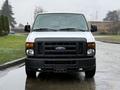 A 2013 Ford E-350 van is displayed head-on with a white exterior and black grille showcasing its headlights and large windshield