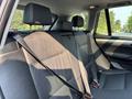 Interior view of the backseat of a 2013 BMW X3 featuring black leather seats with adjustable headrests and seatbelts attached