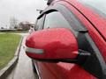 A close-up of the side mirror of a red 2016 Mitsubishi Outlander covered in raindrops with a sleek design and integrated turn signal
