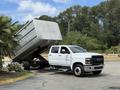 A white 2020 Chevrolet Silverado pickup truck with a dump bed raised is parked at an angle