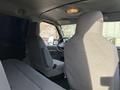 Interior view of a 2011 Ford Econoline showing the driver's seat and passenger seat with gray upholstery and a simple dashboard