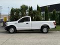 A white 2018 Ford F-150 pickup truck with a regular cab and standard bed parked sideways with chrome wheels