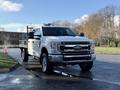 A 2020 Ford F-350 truck with a flatbed in front view showcasing its shiny chrome grille and chrome wheels