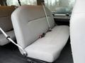 A gray upholstered bench seat with seatbelts inside a 2013 Ford E-350 van