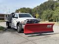 A 2013 RAM 5500 truck equipped with a large red snow plow attached to the front and a flatbed in the rear